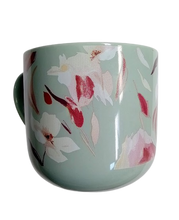 Load image into Gallery viewer, A green ceramic mug with a floral pattern of pink and white flowers and leaves.
