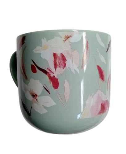 A green ceramic mug with a floral pattern of pink and white flowers and leaves.